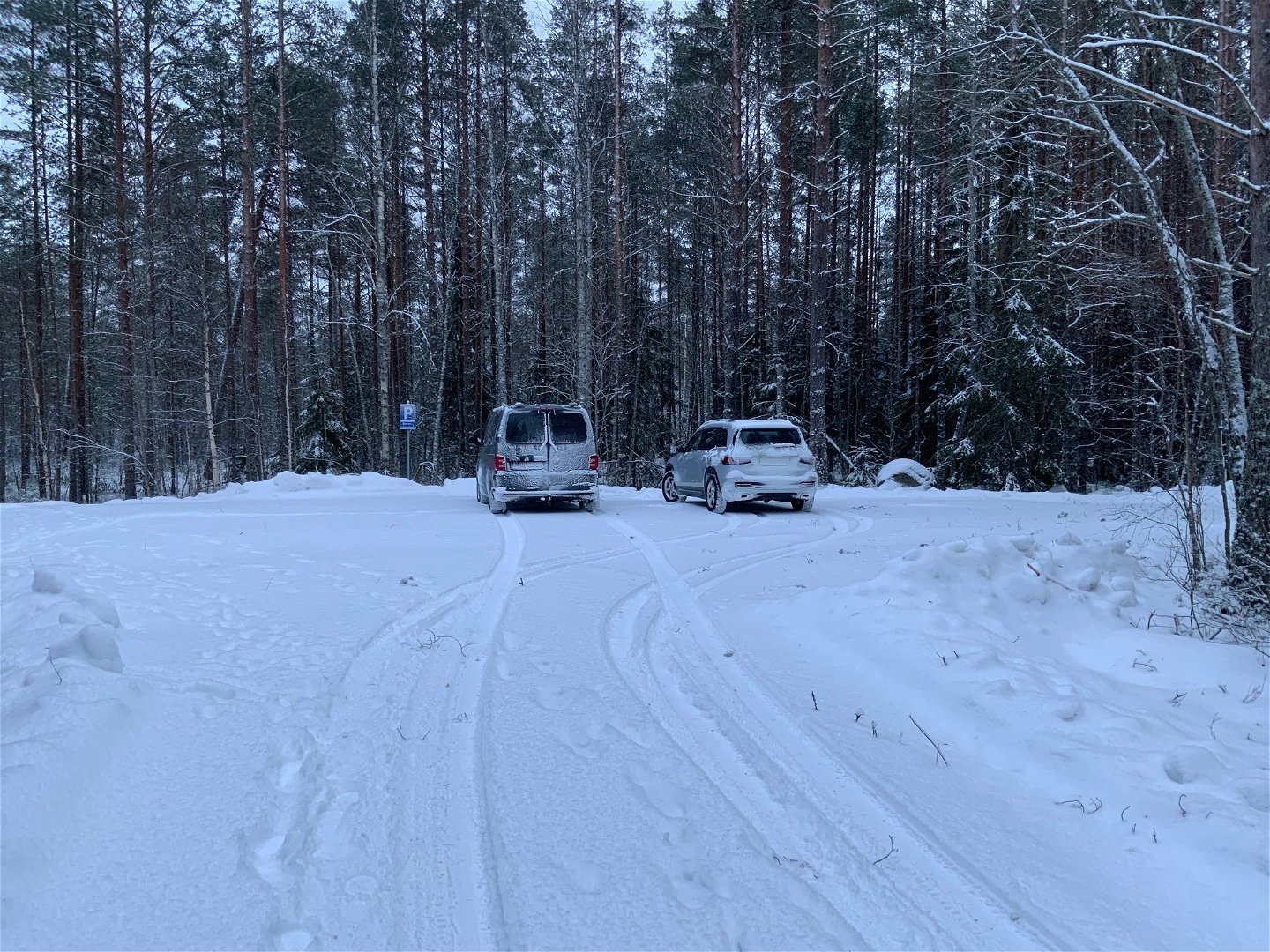 En snöig parkering där två bilar står parkerade.