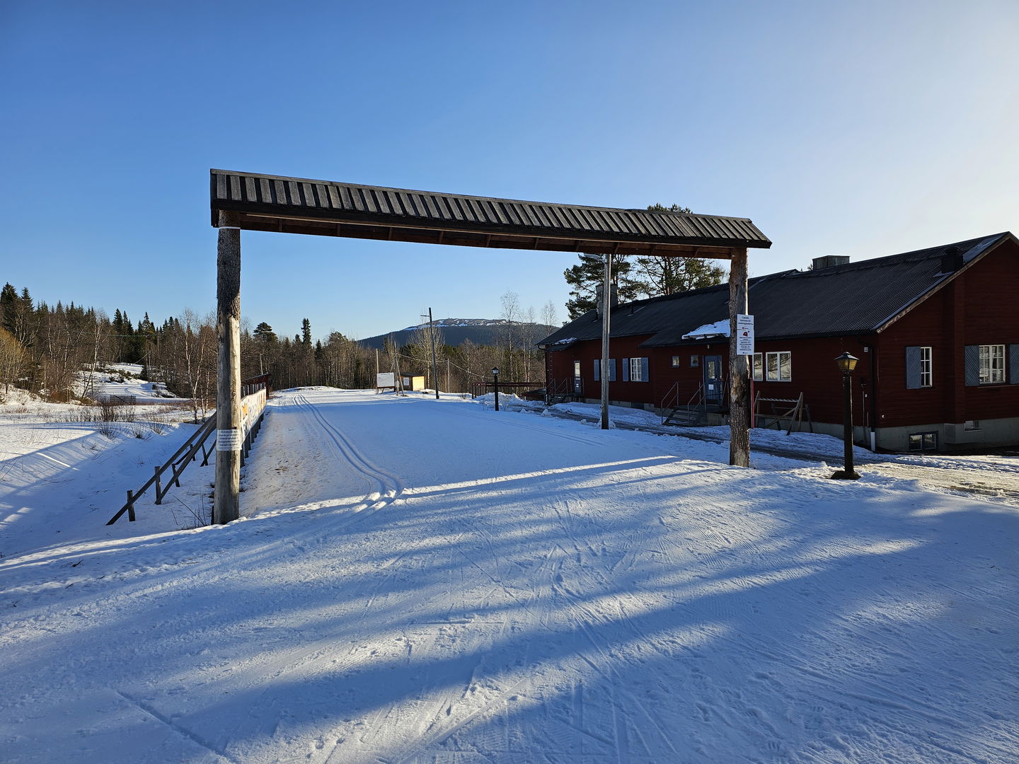 En startportal i trä över pistade skidspår.