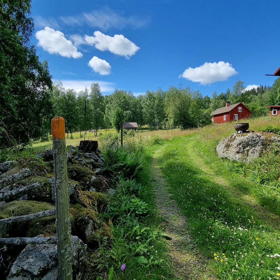 Stenmur, vandringsstolpe och en röd stuga