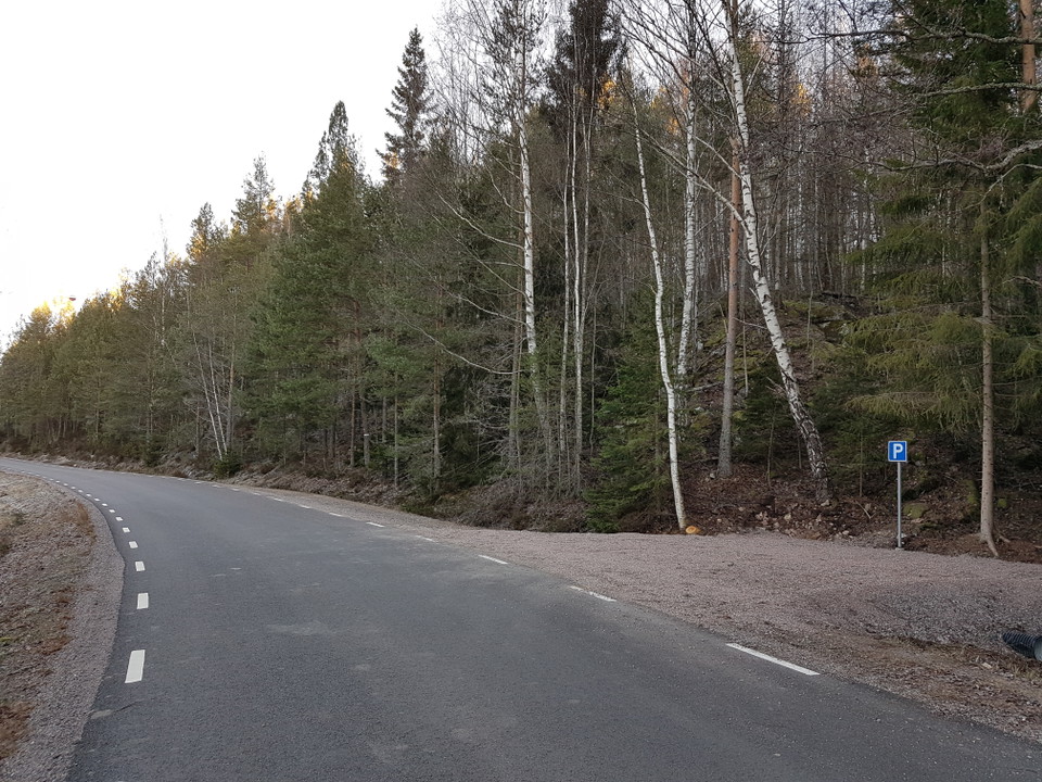 Grusad parkering med plats för flera bilar intill vägkanten.
