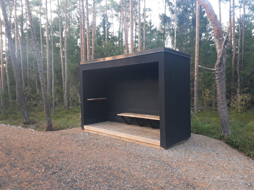 Vindskydd med skog bakom.