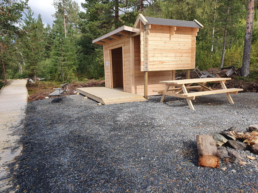Bänk, informationstavla och uthus