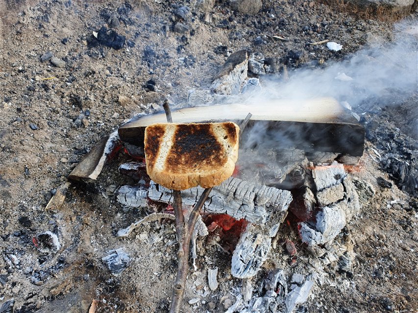 En lite bränd rostmacka som hålls över en eld.