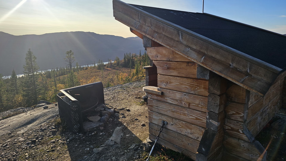Hörnet av ett timrat vindskydd med en vy mot fjäll i bakgrunden