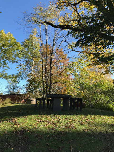 Ett kvarnhjul har blivit bordsskiva, omgivet av sittplatser. En av flera sittplatser på Mjölby hembygdsområde