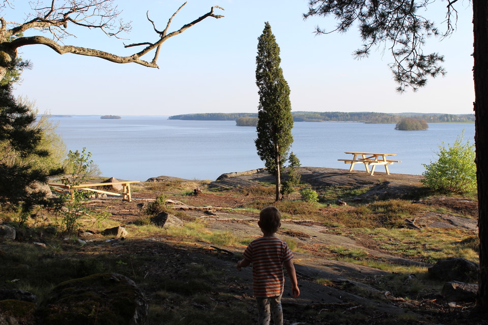 Ett barn går ut mot ett par bänkbord som står på höga klippor.