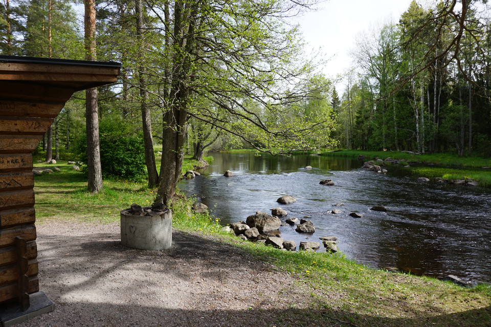 Rastplats innan badplatsen med vindskydd och eldstad och utsikt över ån