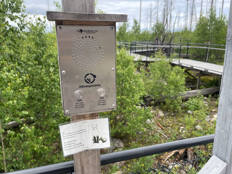 En silverfärgad låda på en trästople. Lådan har två knappar och flertalet små hål på framsidan.