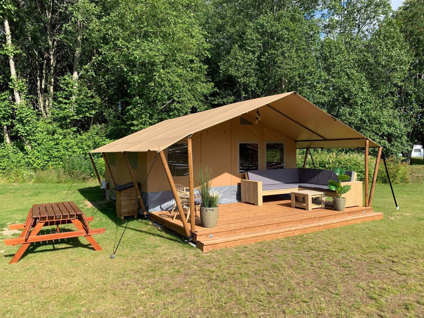 Ett beige tälthus med veranda.