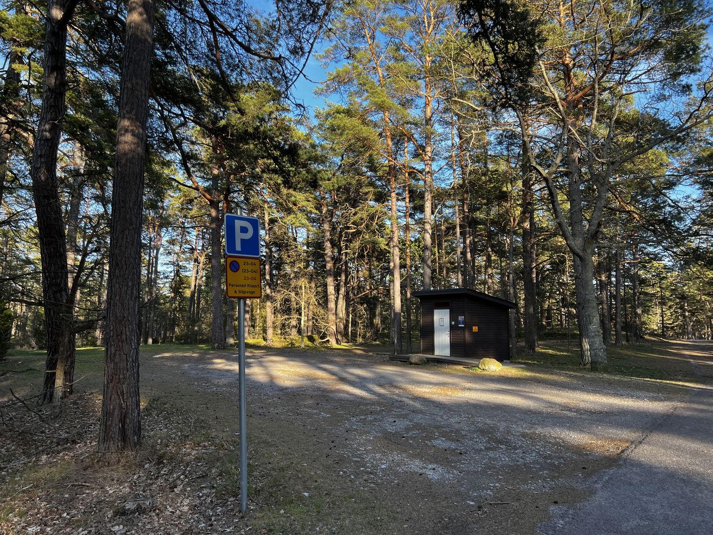 grusparkering med dass i bakgrunden