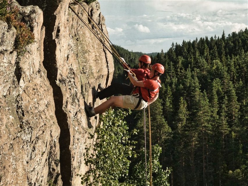 Picture of people climbing down a rock wall via ropes