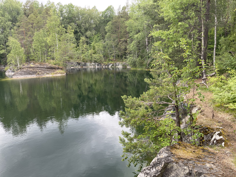 Vattenfyllt stenbrott kantad av skog.
