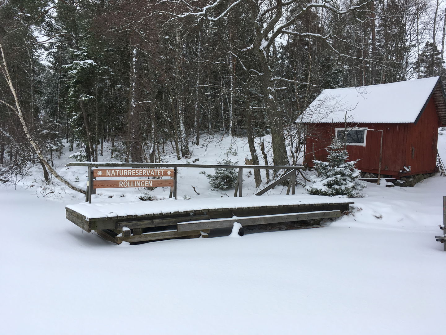 Vid en liten bod står en snötäckt brygga. Det finns inget öppet vatten så bryggan omringas av ett snötäcke.