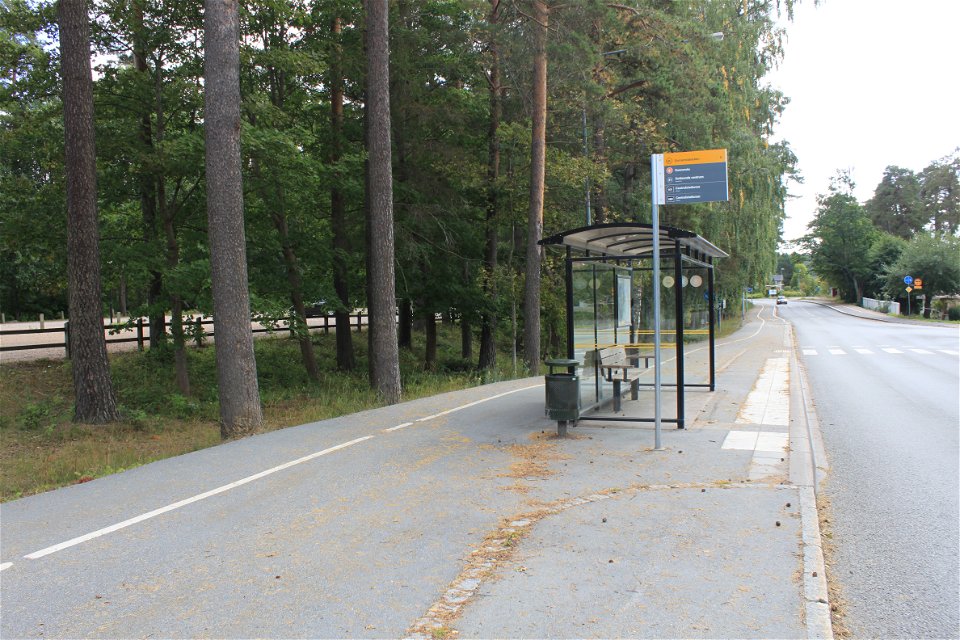 En busshållsplats med inglasad busskur står på en asfalterad gång- och cykelväg.