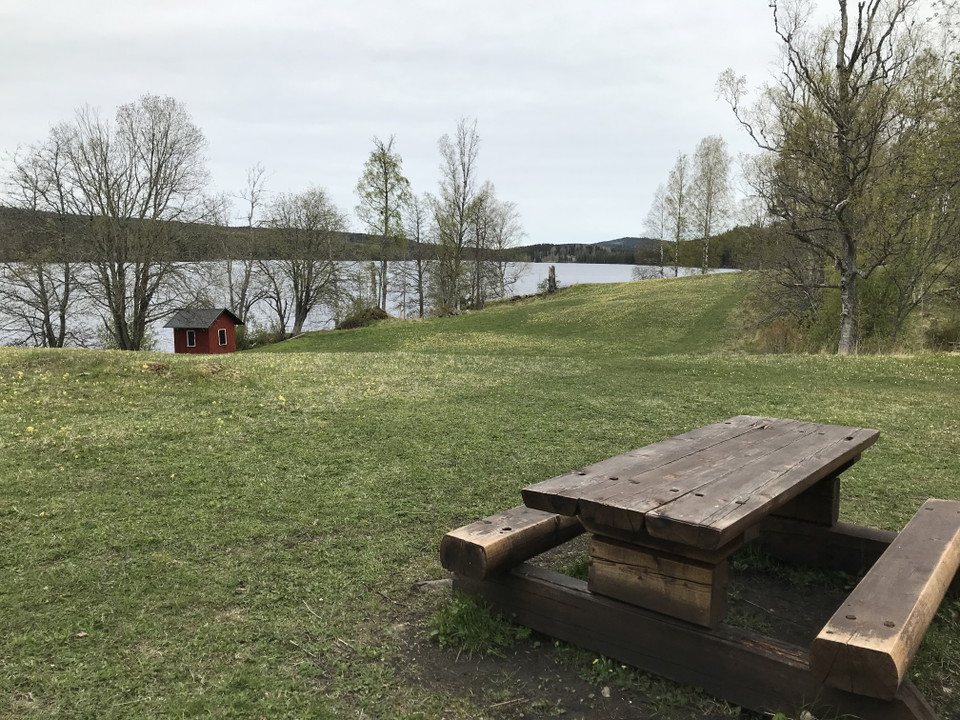 Rastplats med utsikt över slåtteräng och sjö.