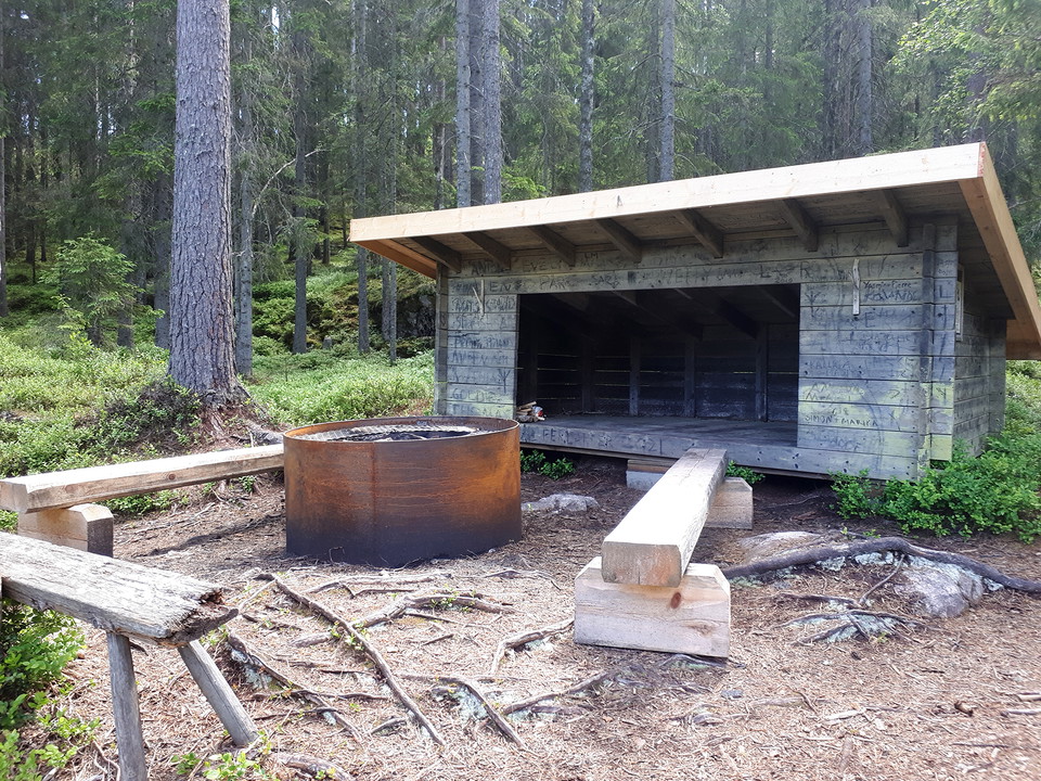 Rund grillstad med bänkar vid vindskydd.