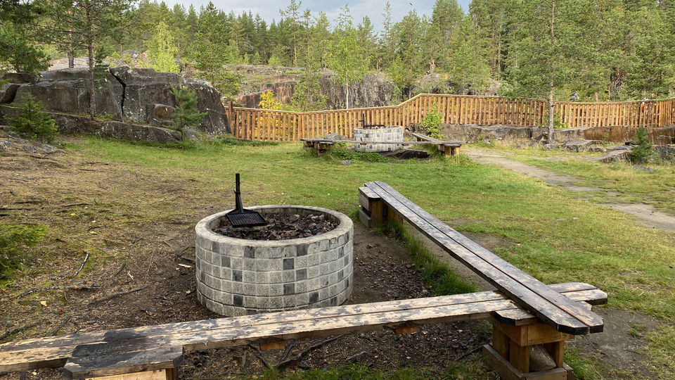 En eldstad med bänkar runt omkring i ett snöigt landskap. 