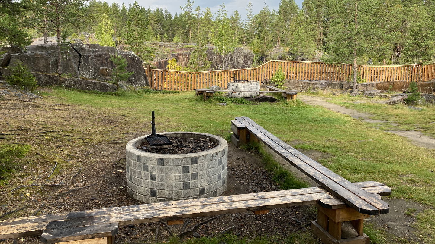 En eldstad med bänkar runt omkring i ett snöigt landskap. 