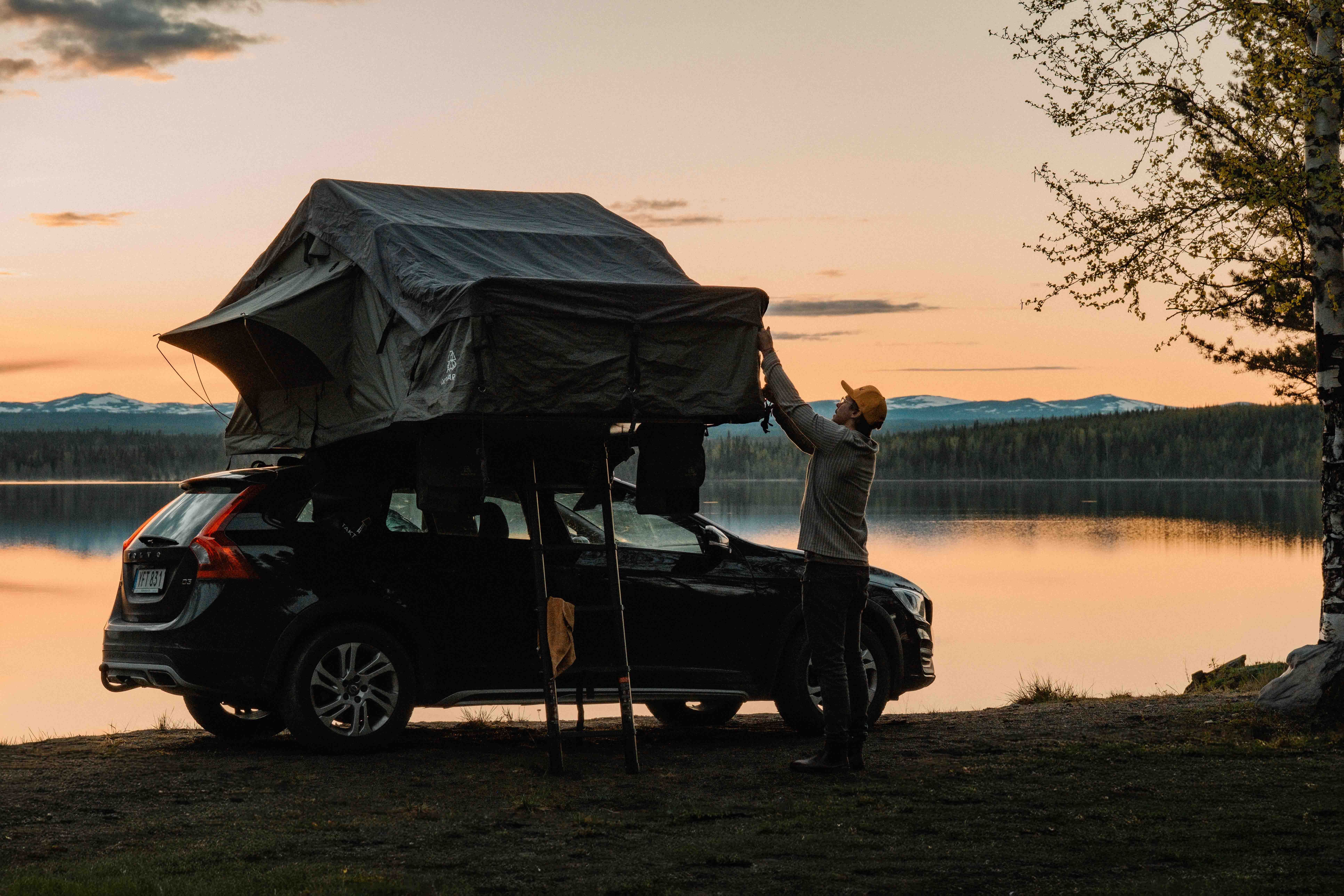Montering av taktält framför sjö i solnedgång