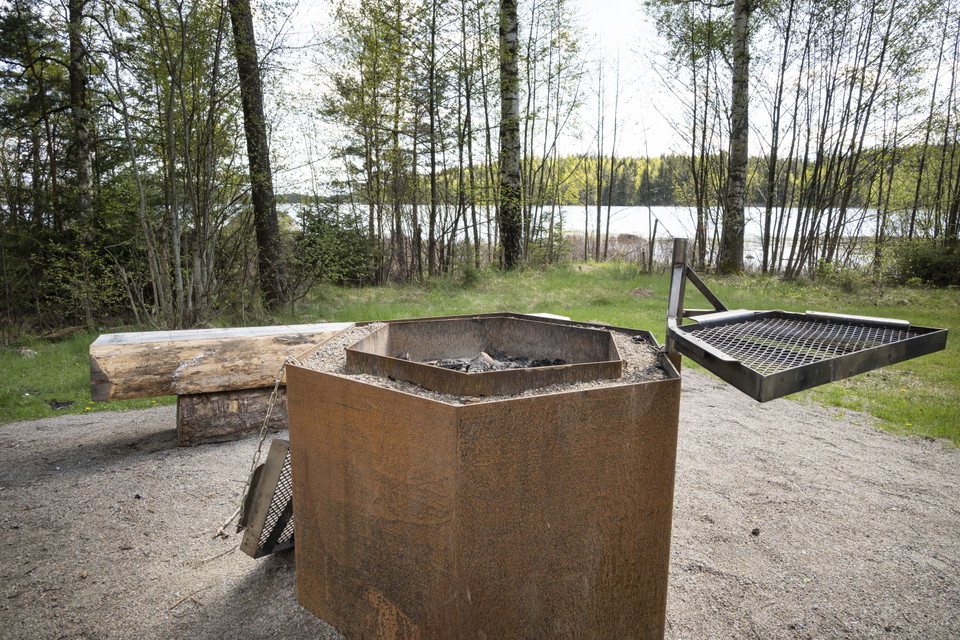 Grillplats med galler och bänk. Sjö och gräs.