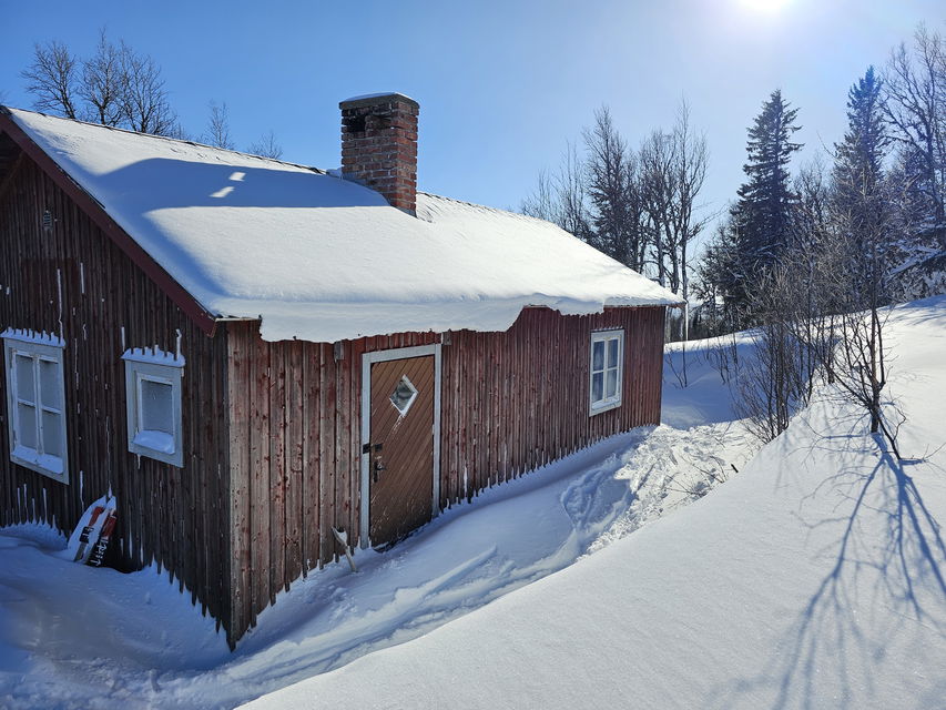 Röd liten stuga inbäddad i snö