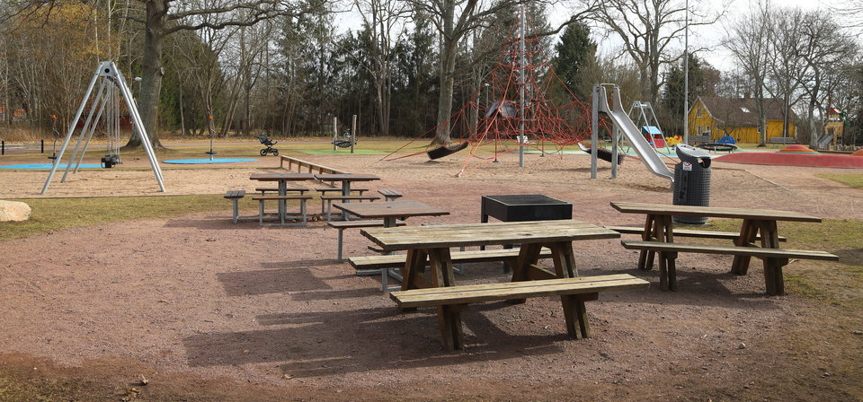 Grill, två bänkbord och sopkorg i lekpark