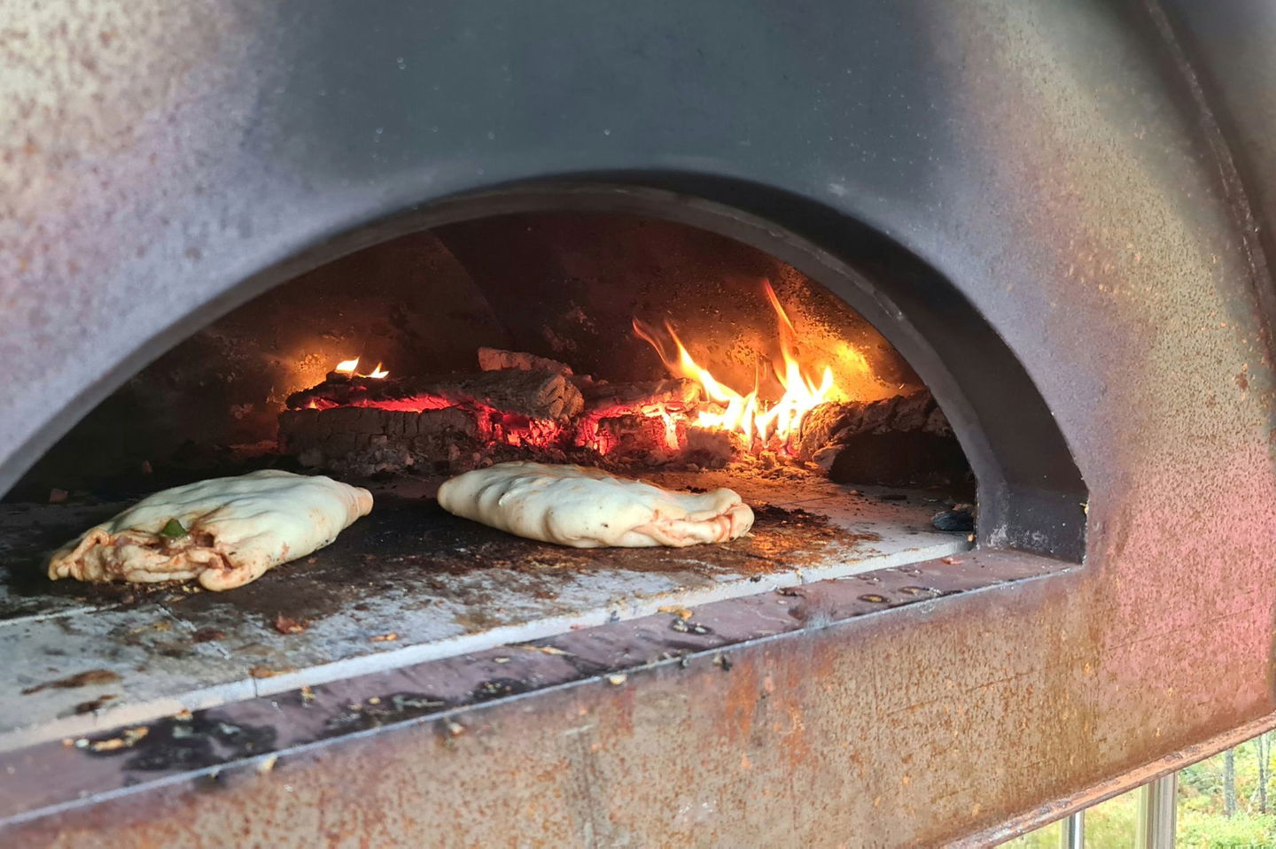 Två hemgjorda pizzor steks i den italienska stenugnen vid Vågsjön utanför Munkfors.