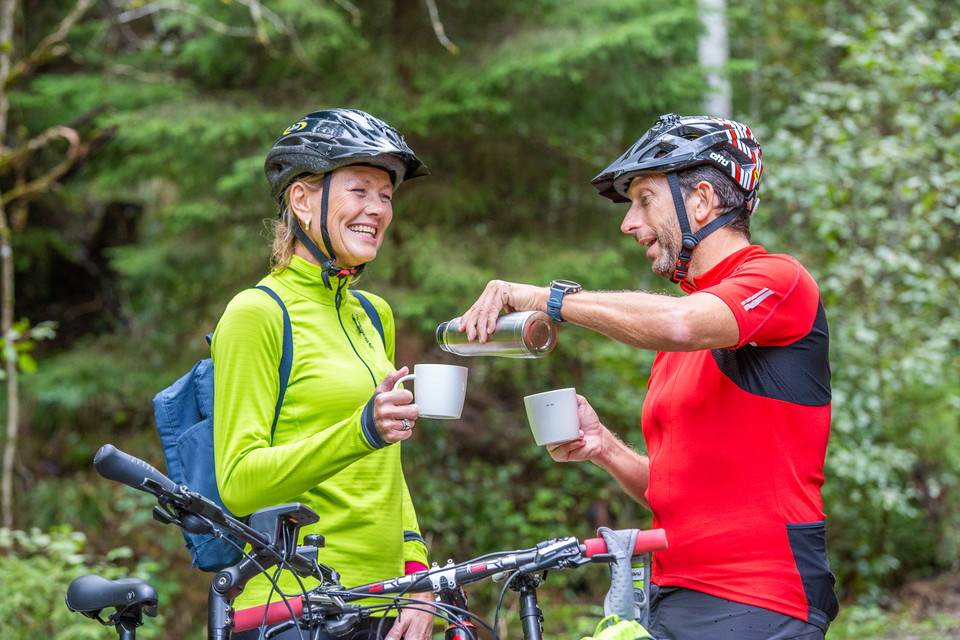 Två cyklister fikar i en skog
