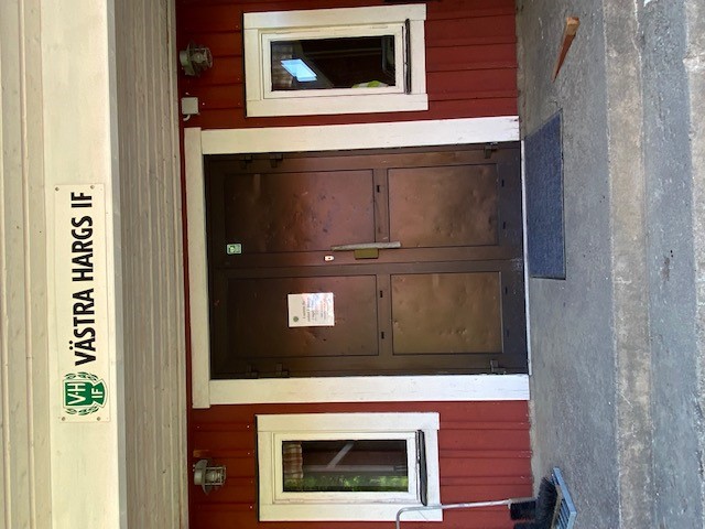 Entrédörr till toaletter i klubbhuset Kulladal. Skylt med texten Västra Hargs IF samt föreningens ogotyp