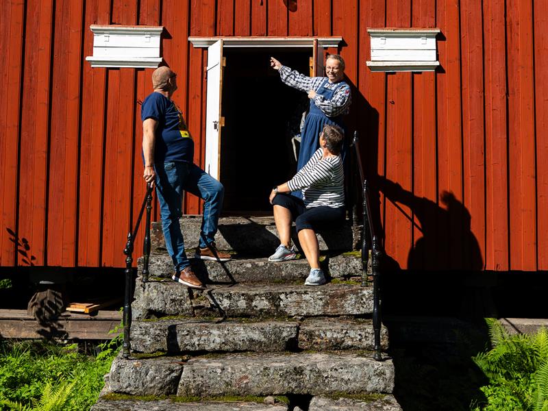 Gjester og museumsvert på en av de gamle steintrappene foran en av bygningene på bygdemuseet