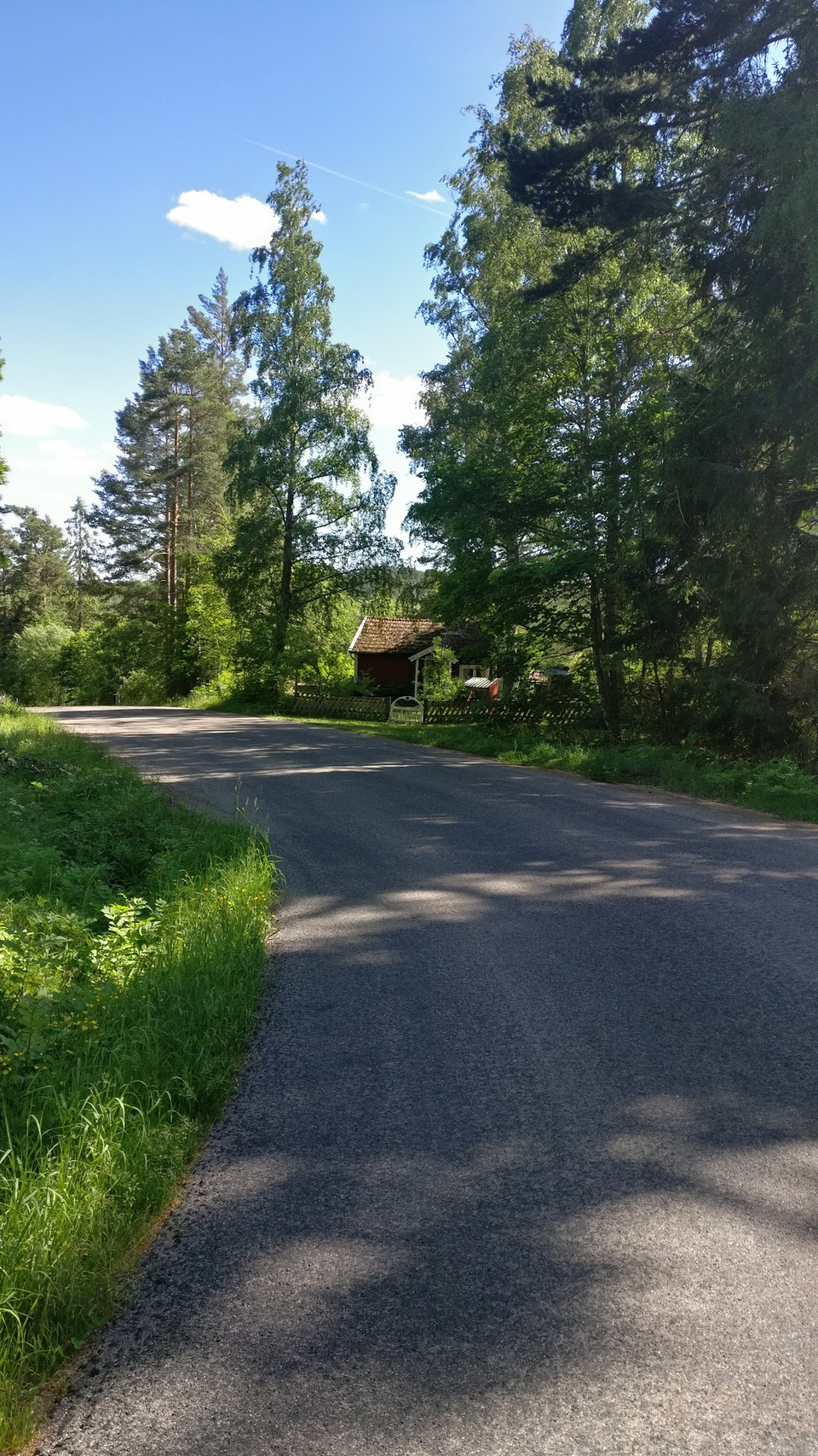En grusväg med ett rött hus i änden av vägen.