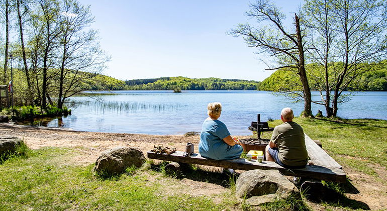 personer som sitter och grillar vida vattnet