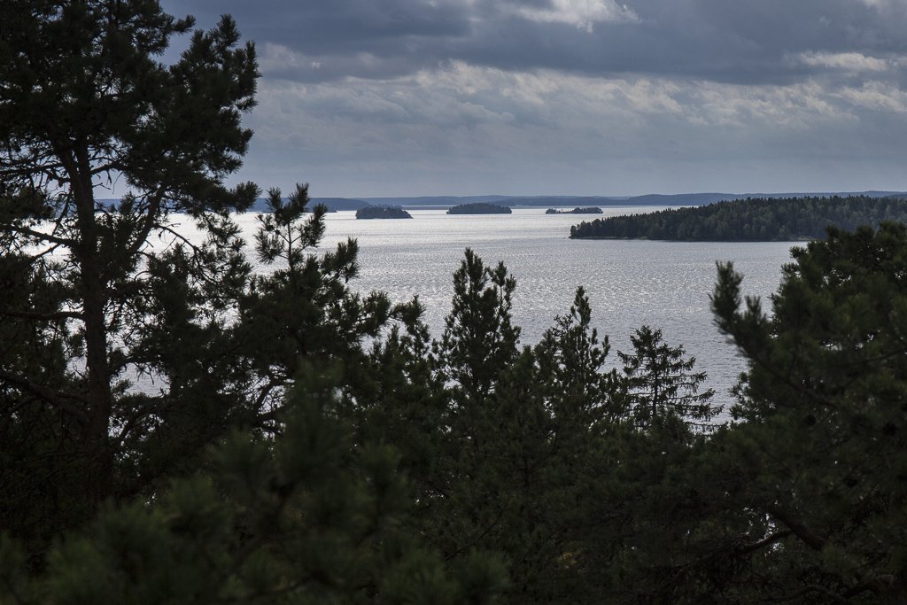 Från en höjd har man utsikt över sjön med flera mindre öar. Många träd står i förgrunden.