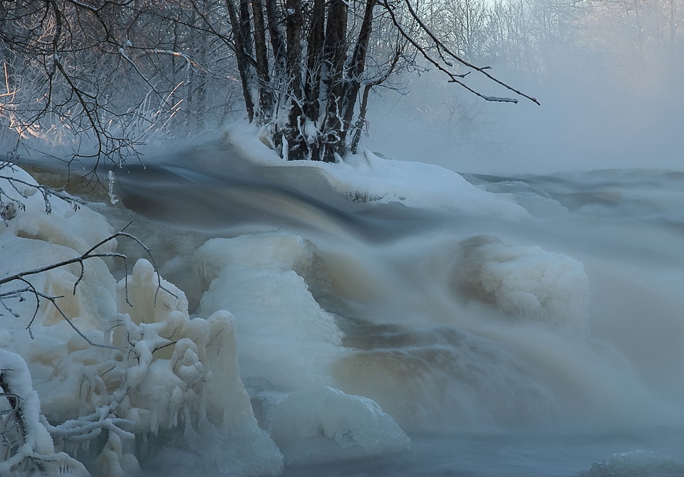 Vattnet forsar fram genom ett vinterlandskap med snö och is.