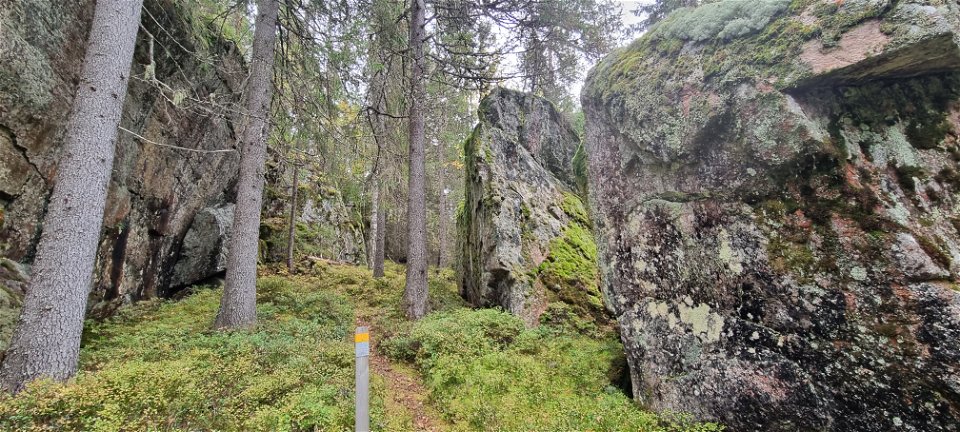 Historisk naturkyrka, stora stenblock intill bergsvägg.
