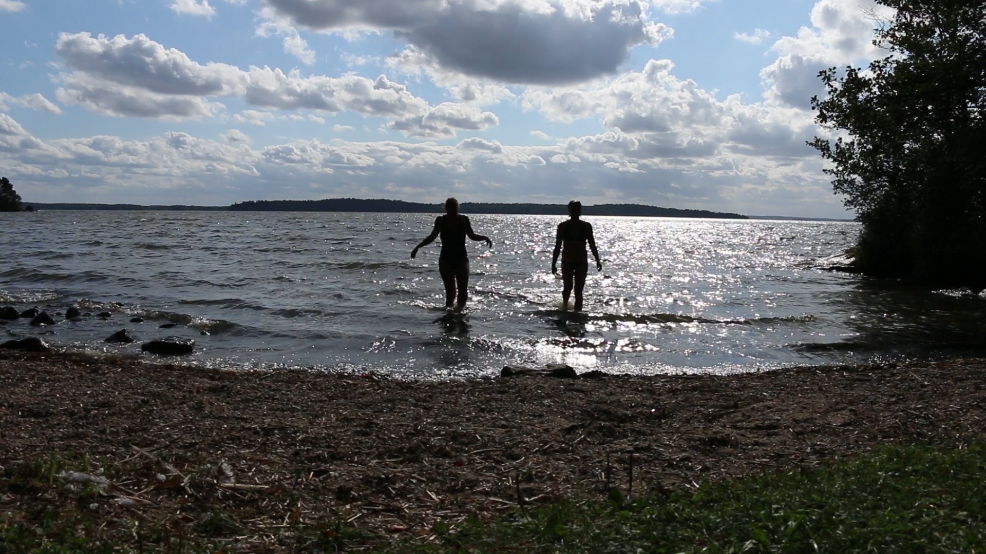 Två personer på väg ut i vattnet för att bada.