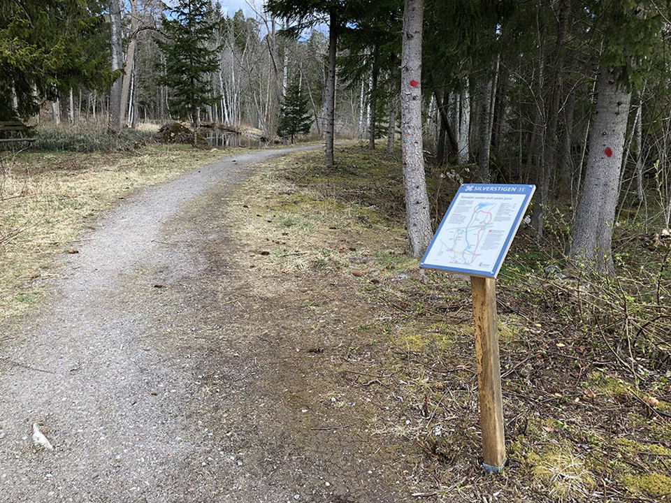 Informationstavla längs grusad stig.