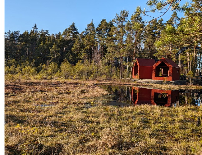 Ett vindskydd med skog i bakgrunden.