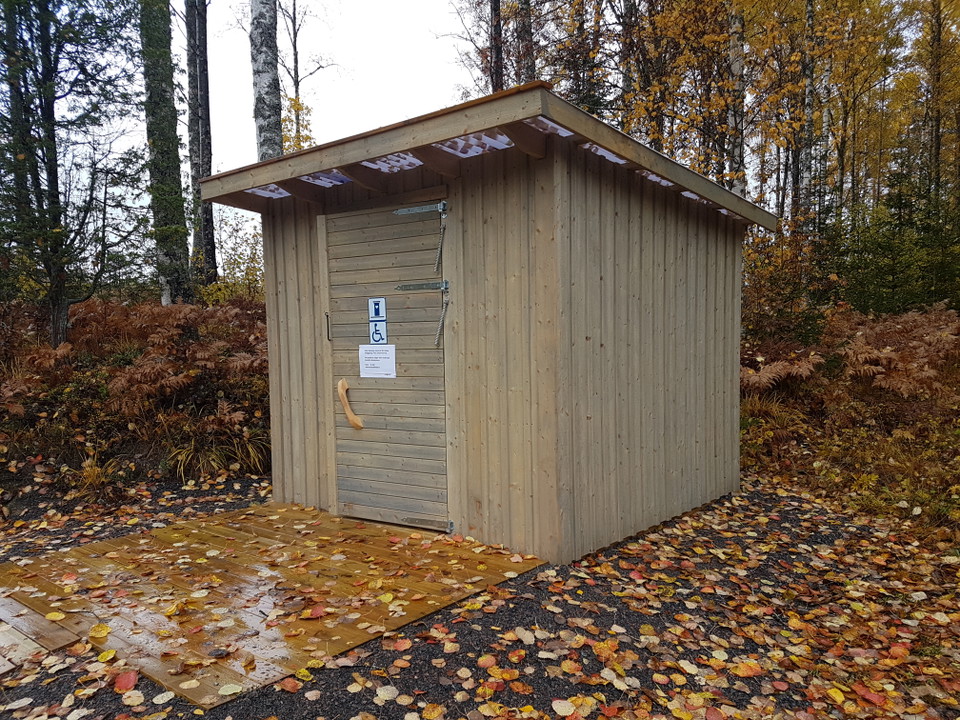 En tillgänglig torrtoalett med plattform utanför dörren.