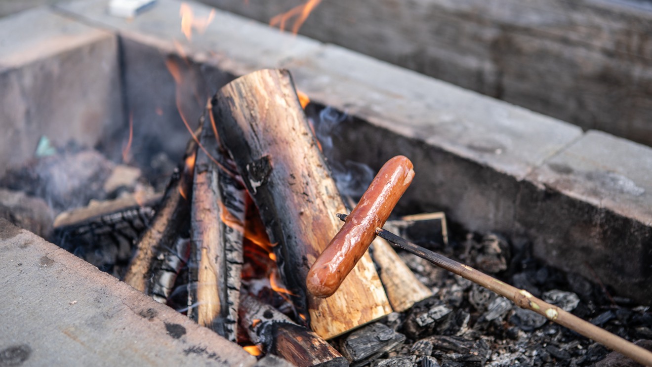 En korv grillas över en öppen eld.
