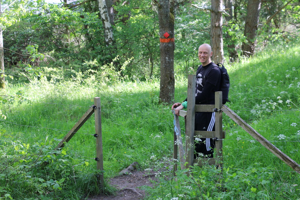 En man öppnar en grind och är på väg att gå in i en hage.