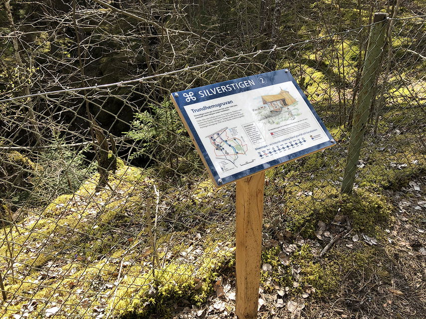 Informationstavla vid inhägnat hål i marken.