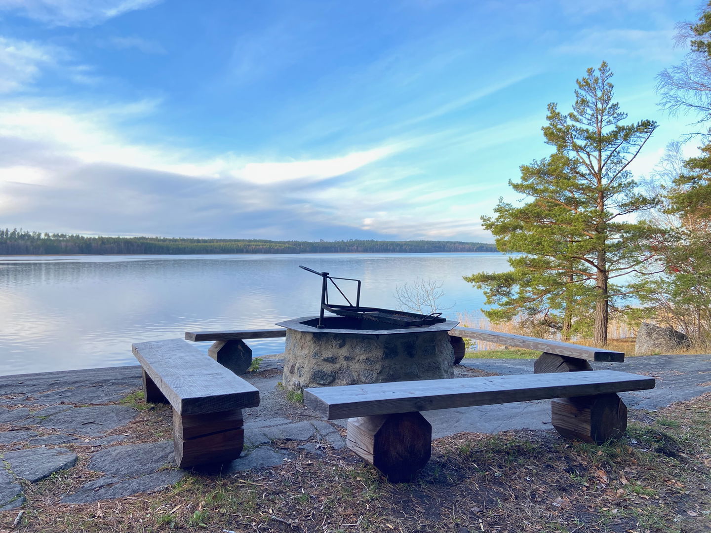 En eldstad med tre bänkar runt, på en klippa med utsikt över vattnet. 