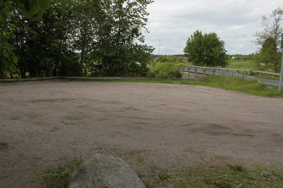 En rymlig, grusad parkeringsplats vid en bro. 