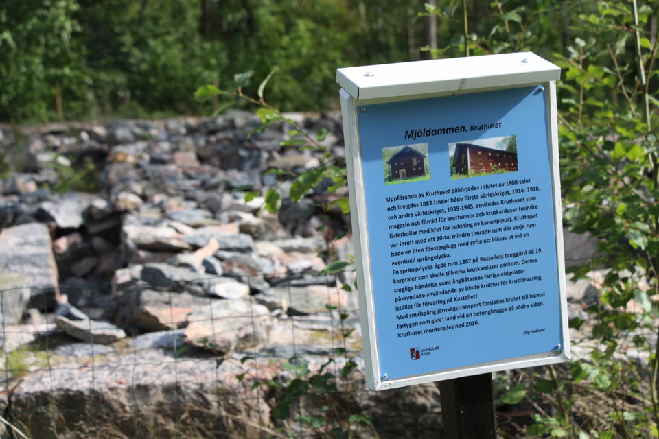 En blå skylt vid en stengrund.