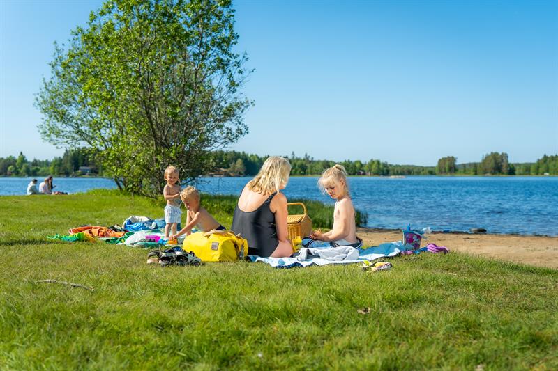 Barn og voksne som koser seg på gresset på Lundebyvannet