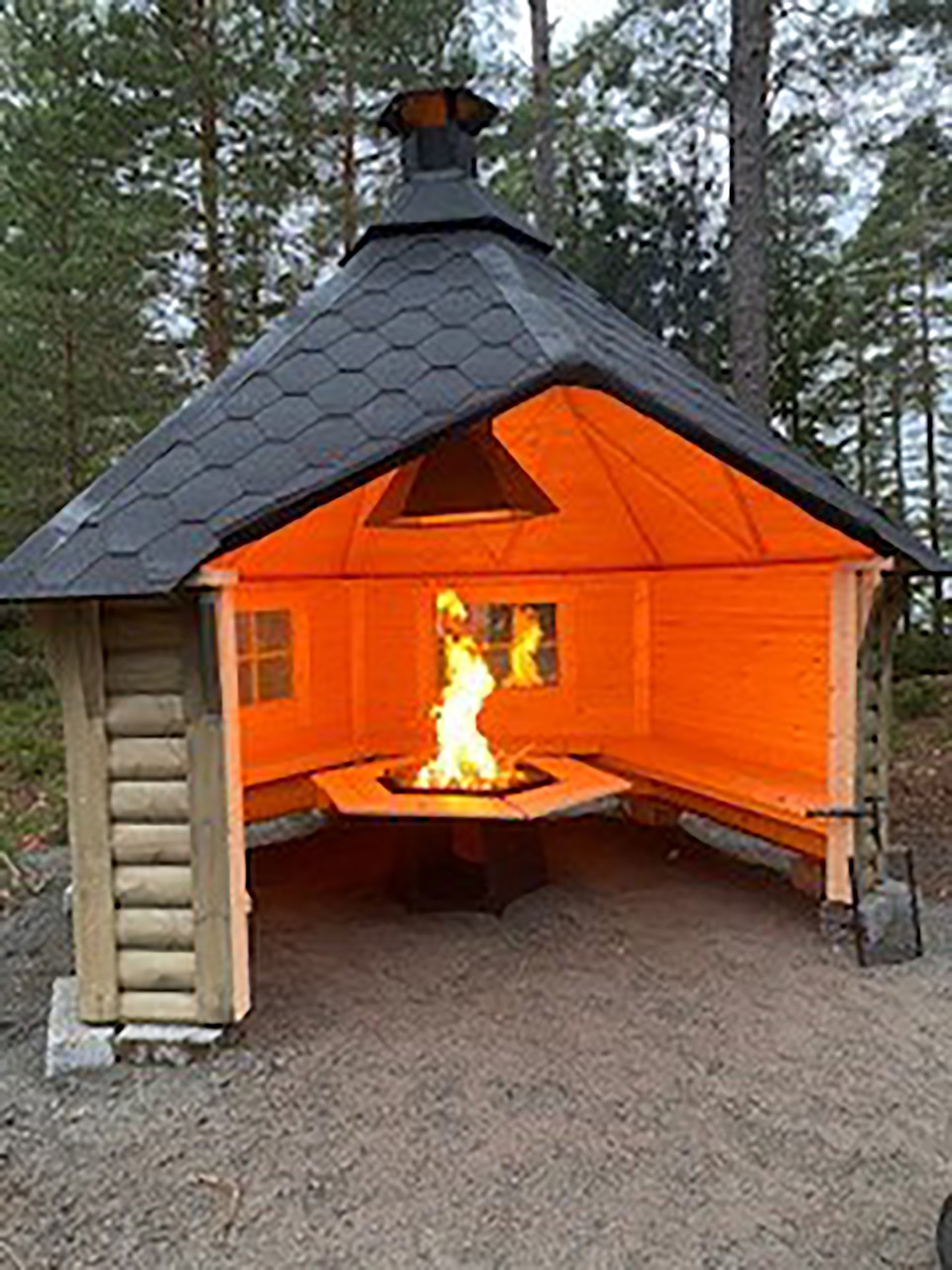 Grillkåta, med både väggar och tak. I mitten brinner en eld.