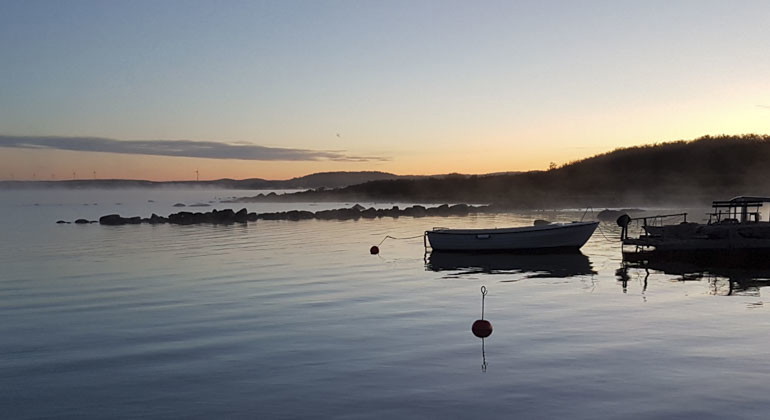 vy över en båt som ligger i havet fastspänd mot en brygga kvällstid