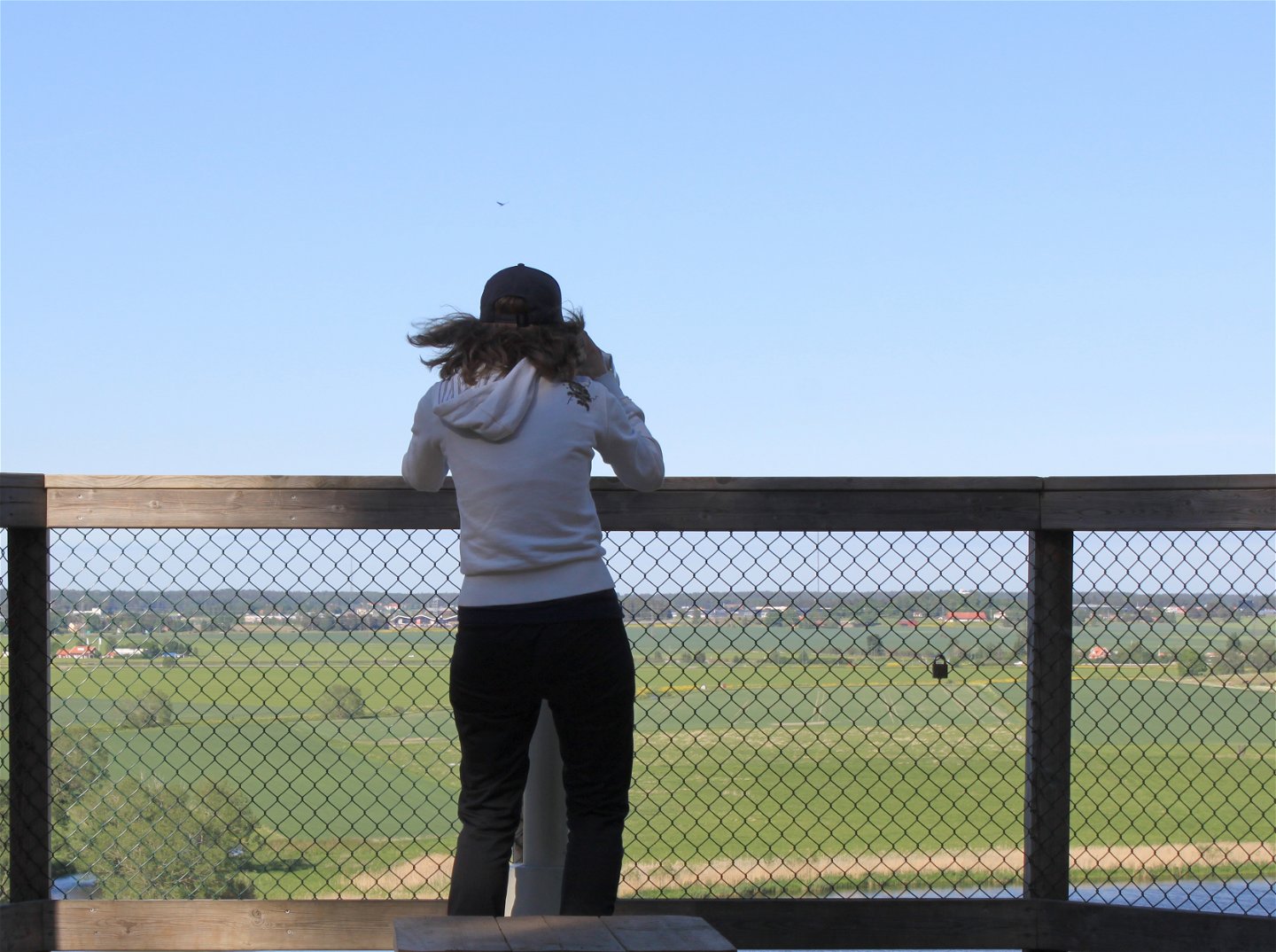 En kvinna står vid skyddsräcket på utsiktsplattformen och blickar ut över Fyrisån.