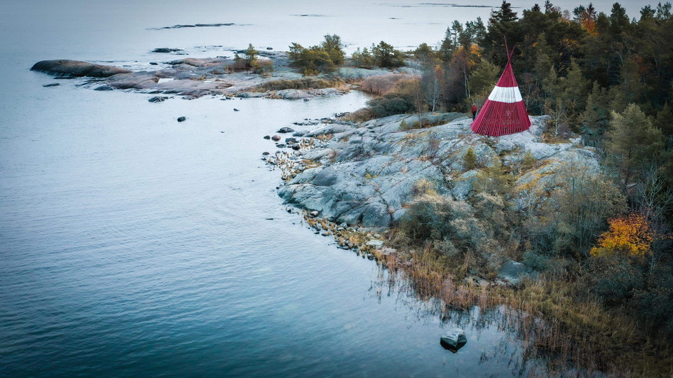 Ett rött och vitt sjömärke på en klippa vid havet.